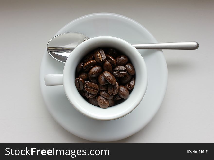 Coffee beans in white coffee cup with a spoon. Coffee beans in white coffee cup with a spoon