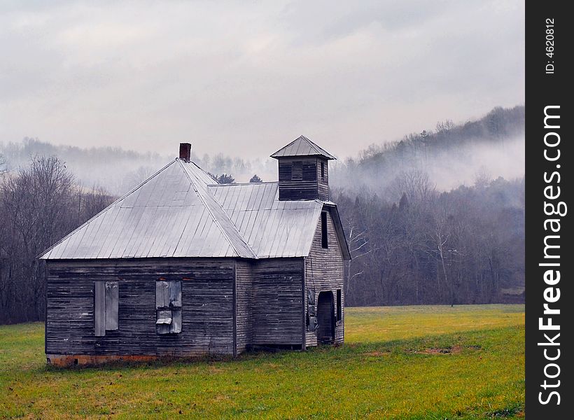 An old tin-roofed schoolhouse, a fog rising above the bare trees in the hills beyond. An old tin-roofed schoolhouse, a fog rising above the bare trees in the hills beyond.