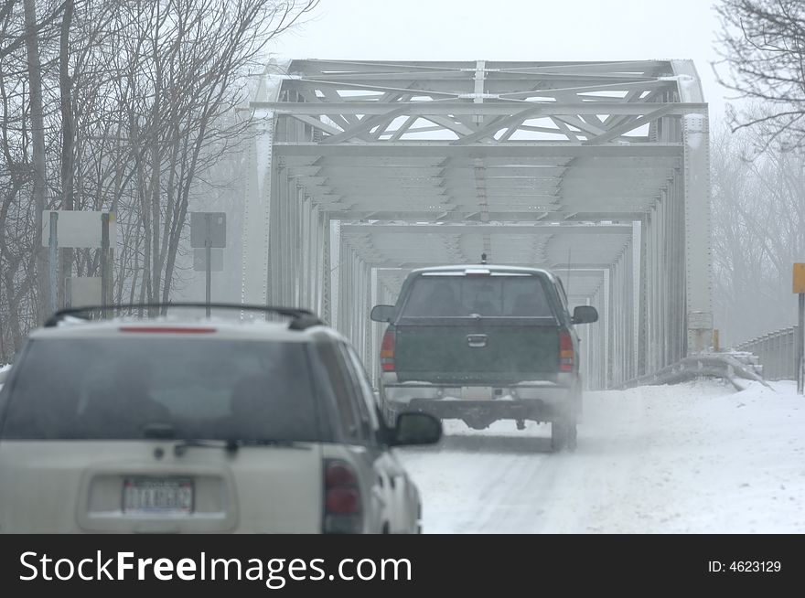 Vehicles crossing a bridge during a blizzard. Vehicles crossing a bridge during a blizzard.