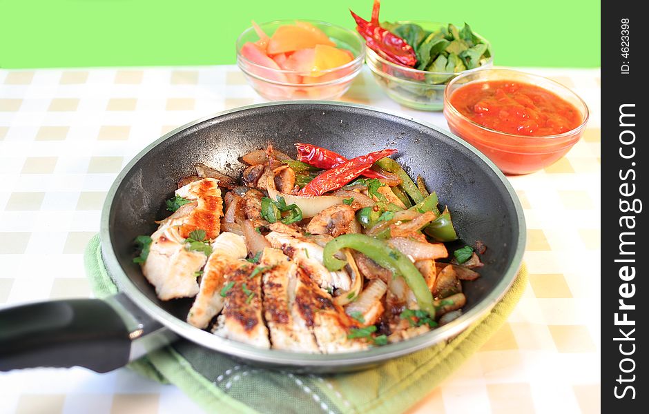 Preparing delicious and colorful mexican style chicken fajitas with vegetables, and salsa. Preparing delicious and colorful mexican style chicken fajitas with vegetables, and salsa