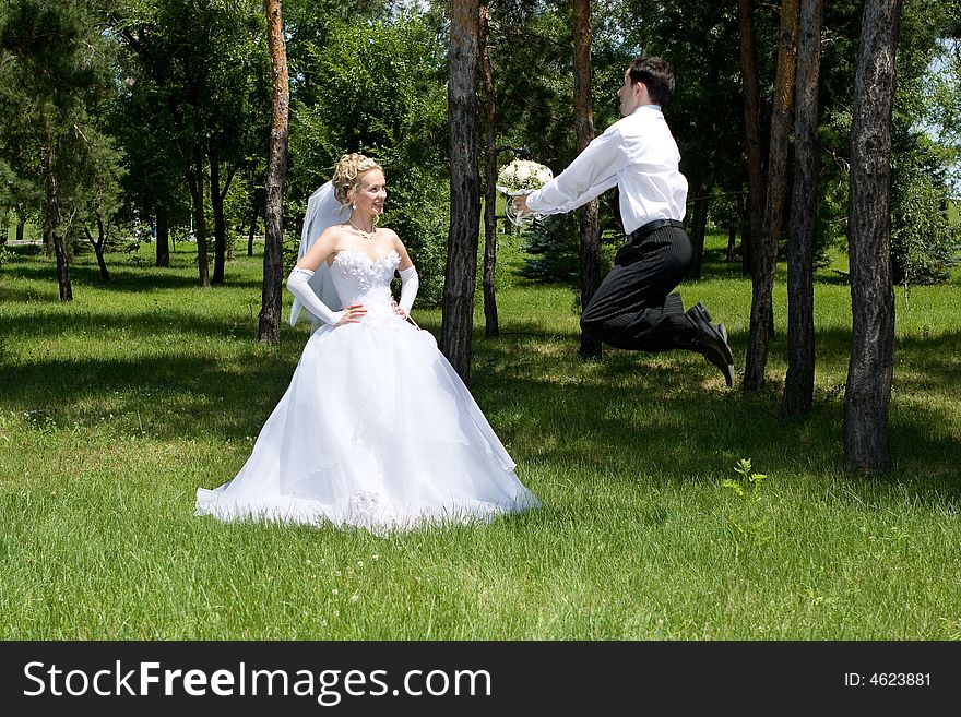 Groom with a wlower bouquet jumps near the bride. Groom with a wlower bouquet jumps near the bride