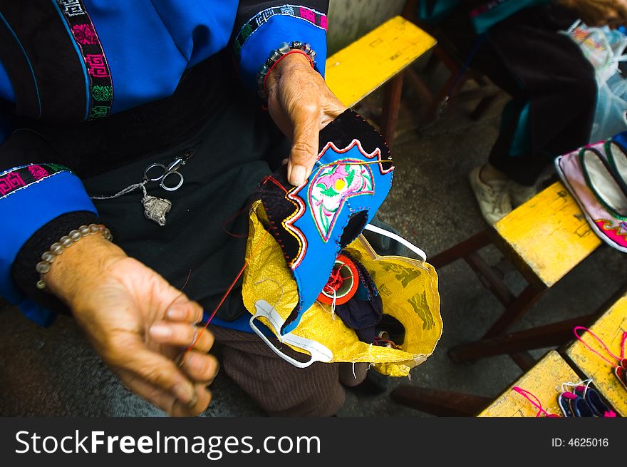 Miao national minority's old woman is Sewing her national clothing in China