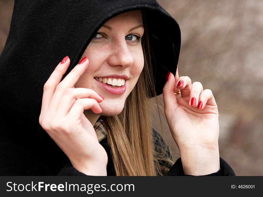 The face and hands of the young girl correcting a black hood