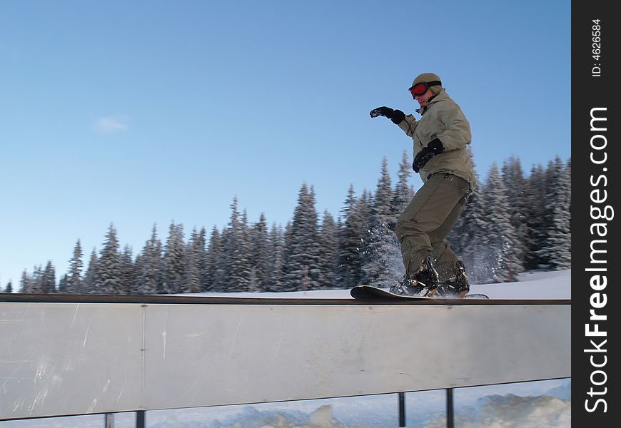 Freeride snowboarder sliding on rail.