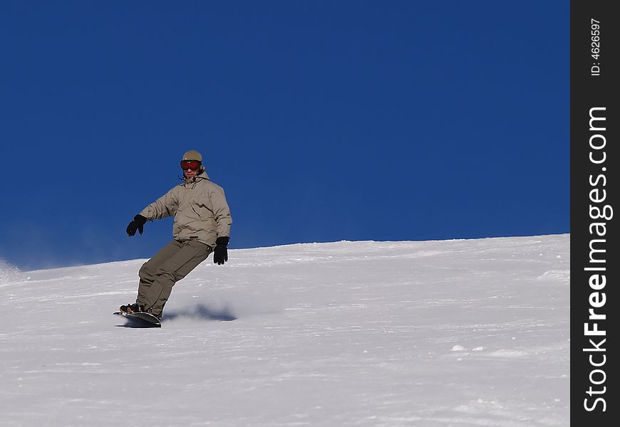 Snowboarder guy sliding on the slope.