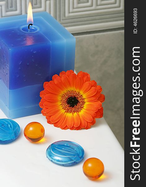 Blue candle with decorative stones,bath oil and orange flower. Blue candle with decorative stones,bath oil and orange flower.