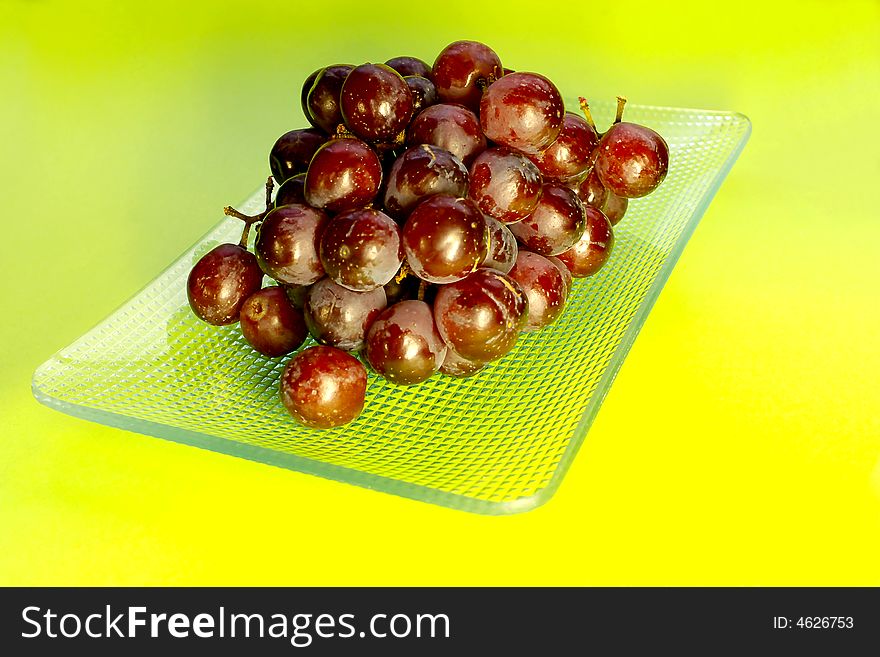 Bunch of red grapes on a grass right-angled plate.