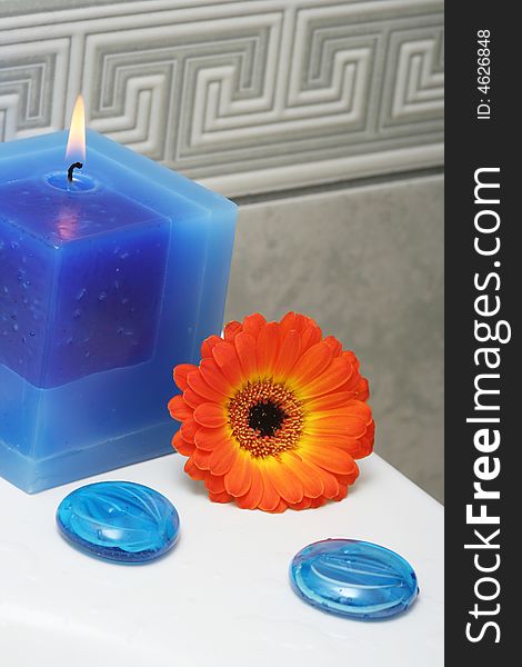 Blue candle with decorative stones and orange flower. Blue candle with decorative stones and orange flower.