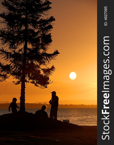 A young family silhouetted against a colourful evening sky. A young family silhouetted against a colourful evening sky