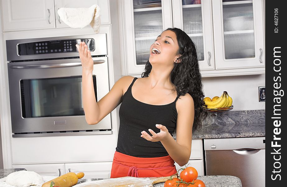 Young woman in kitchen tossing dough in the air. Young woman in kitchen tossing dough in the air