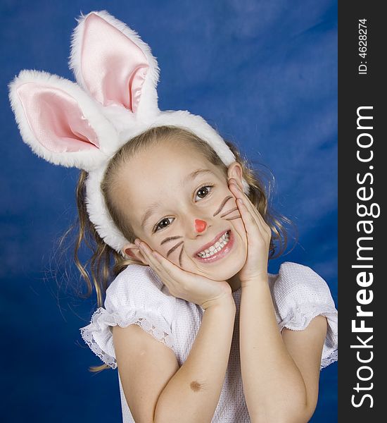 Little smilling girl dressed as bunny over blue background