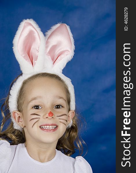 Little smilling girl dressed as bunny over blue background