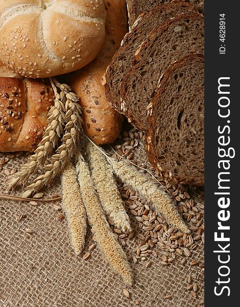 A close up of a different bread with wheat grains and stalks placed next to it.
. A close up of a different bread with wheat grains and stalks placed next to it.