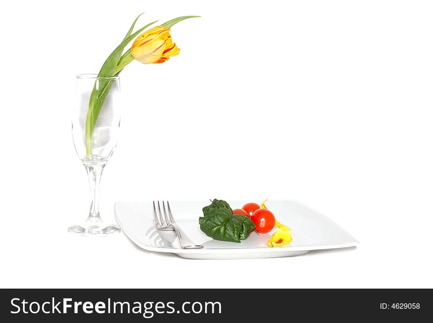 Still life of vegetables on a plete and flower in a glass. Still life of vegetables on a plete and flower in a glass