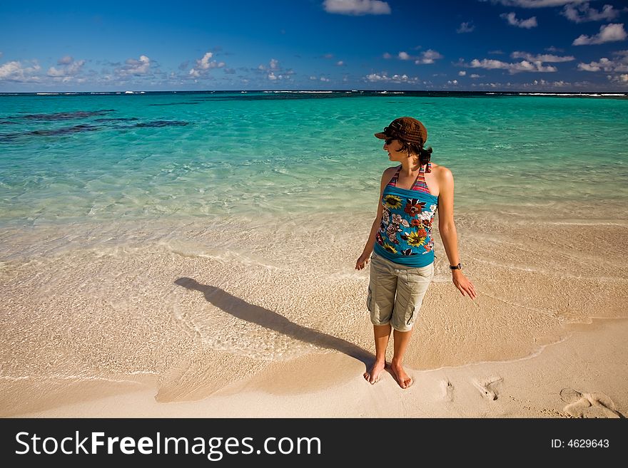 Young woman standing on tropical white sand beach by turquoise waters. Young woman standing on tropical white sand beach by turquoise waters