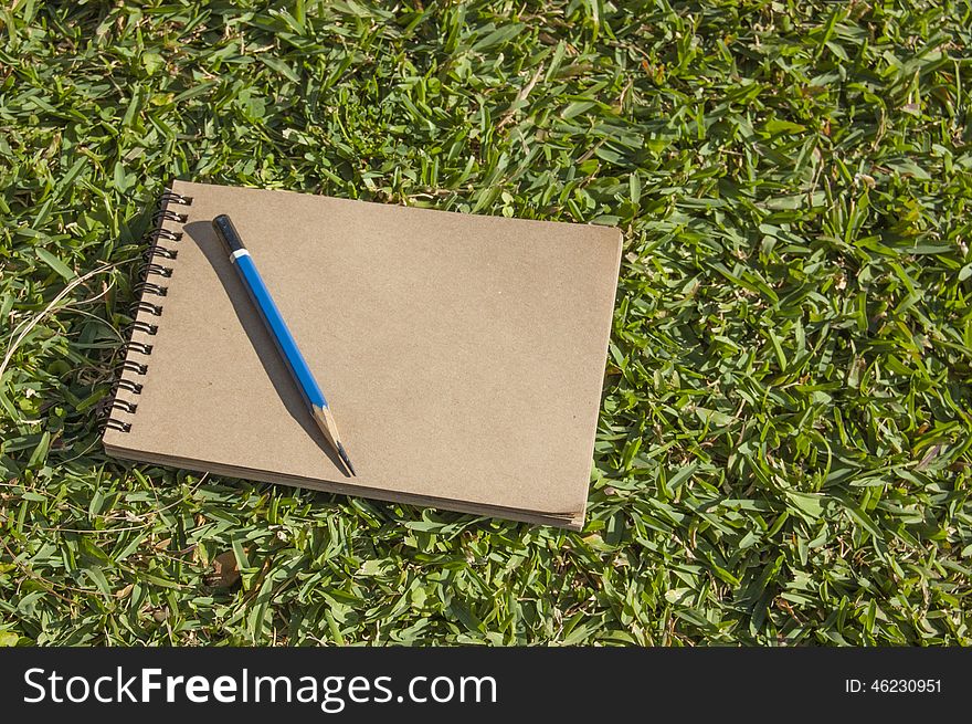 Notebook for sketching lying on green grass. Notebook for sketching lying on green grass