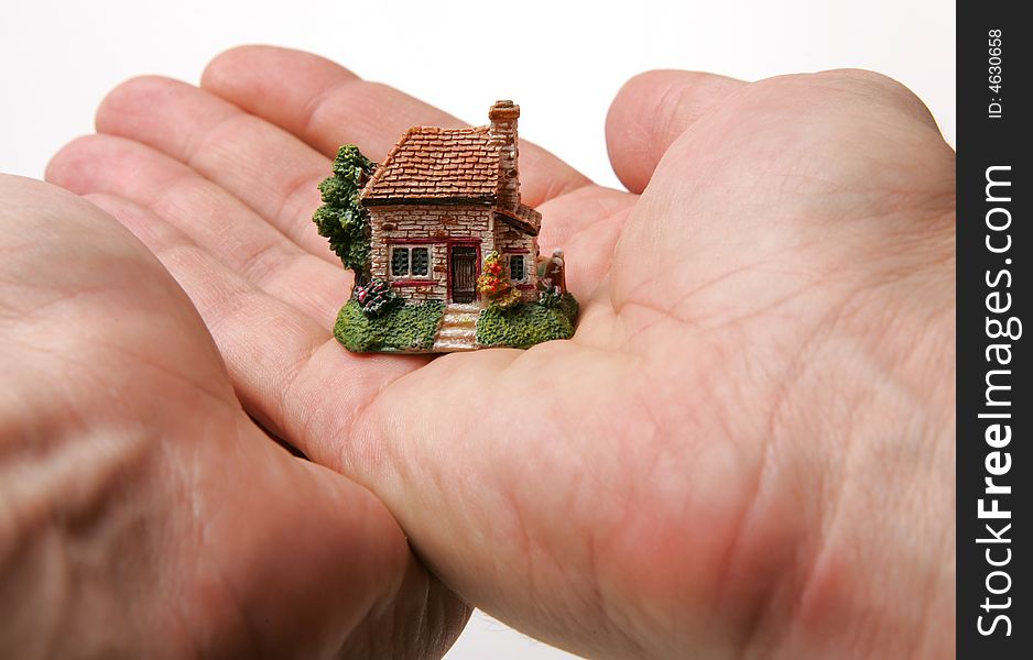 A small porcelain figurine of a country house supported by hands. A small porcelain figurine of a country house supported by hands.