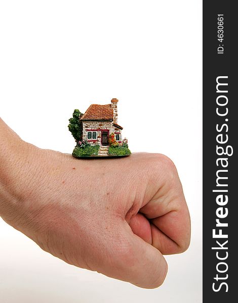 A small porcelain figurine of a country house supported by fist. A small porcelain figurine of a country house supported by fist.