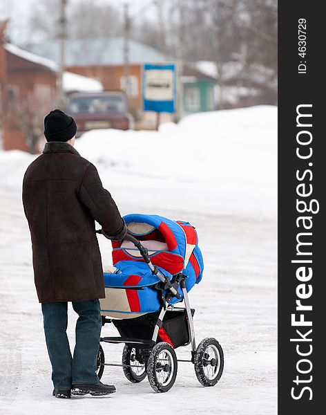 Father with baby stroller in winter walking