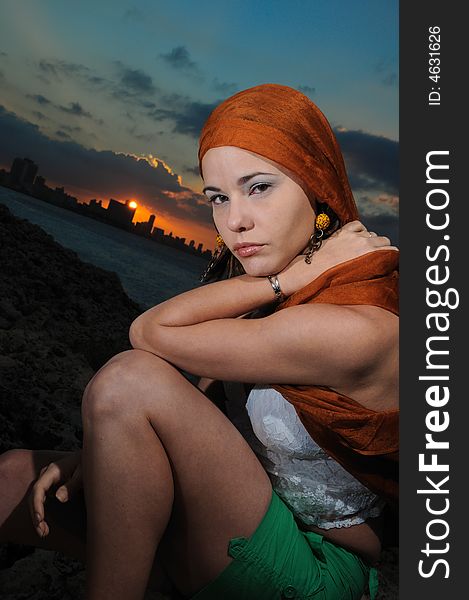 Fashion model sitting outdoors at sunset - havana skyline on the background. Fashion model sitting outdoors at sunset - havana skyline on the background