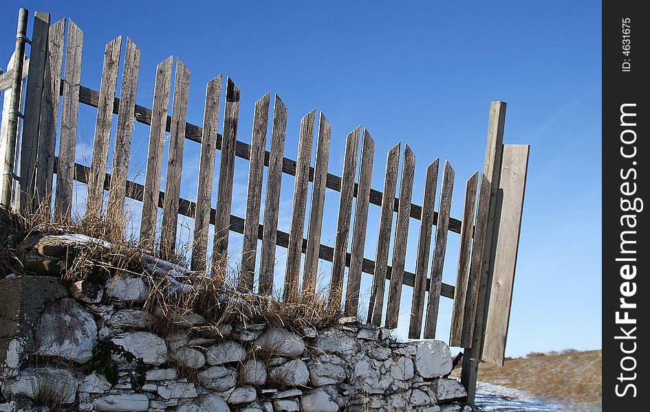 Old wooden picket fence on stone wall in country