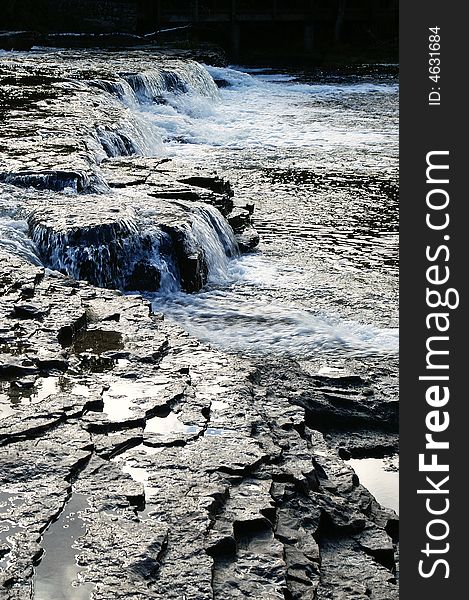 White water flowing over dark rocks in river. White water flowing over dark rocks in river