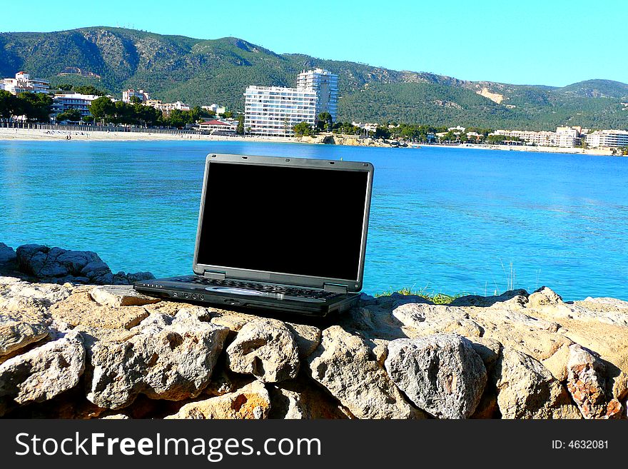 Laptop with beach view behind and blank screen for text. Laptop with beach view behind and blank screen for text