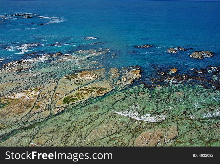 Shallow water covering a wide rock shelf along the Kaikoura coastline in New Zealand. Shallow water covering a wide rock shelf along the Kaikoura coastline in New Zealand