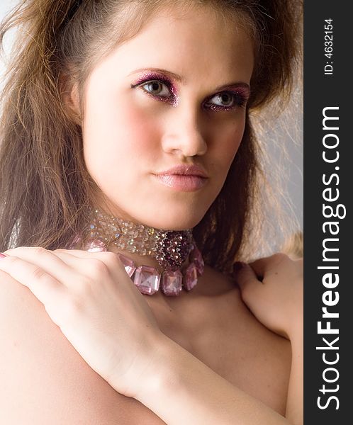 Young beautiful woman with stylish make-up and neck-lace put her hands on bare shoulders. Young beautiful woman with stylish make-up and neck-lace put her hands on bare shoulders