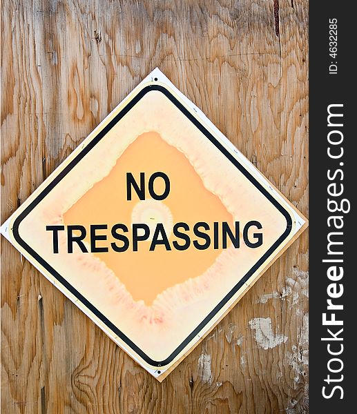 "No Trespassing" sign on grunge wooden fence