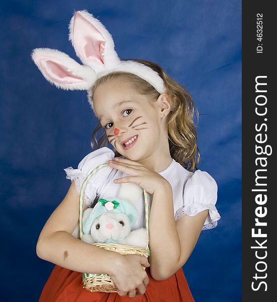 Little girl smilling with bunny in basket over blue background. Little girl smilling with bunny in basket over blue background