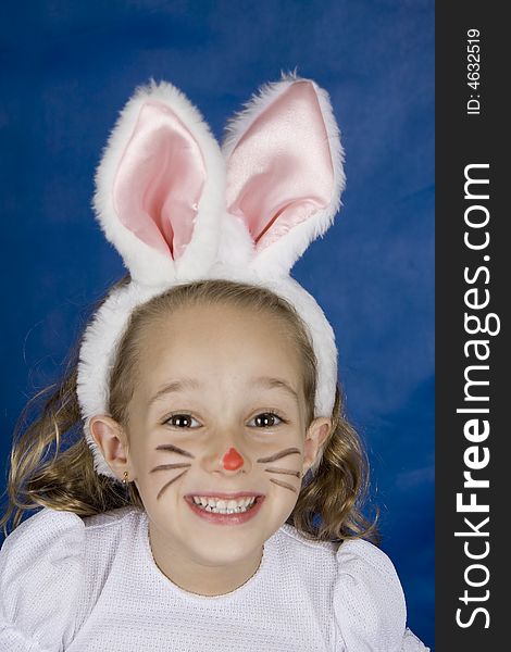 Little girl smilling with bunny ears over blue background. Little girl smilling with bunny ears over blue background