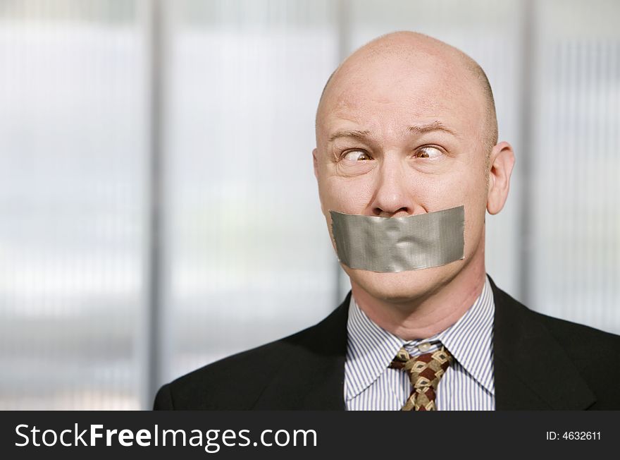 Cross-eyed businessman silenced with duct tape over his mouth. Cross-eyed businessman silenced with duct tape over his mouth