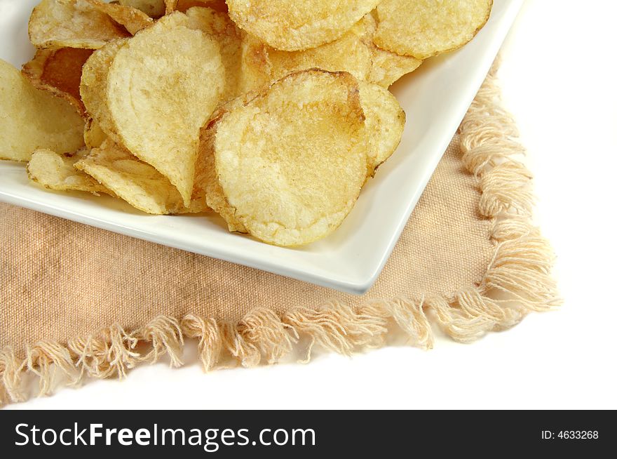 Potato chips close up on a square white dish. Potato chips close up on a square white dish.