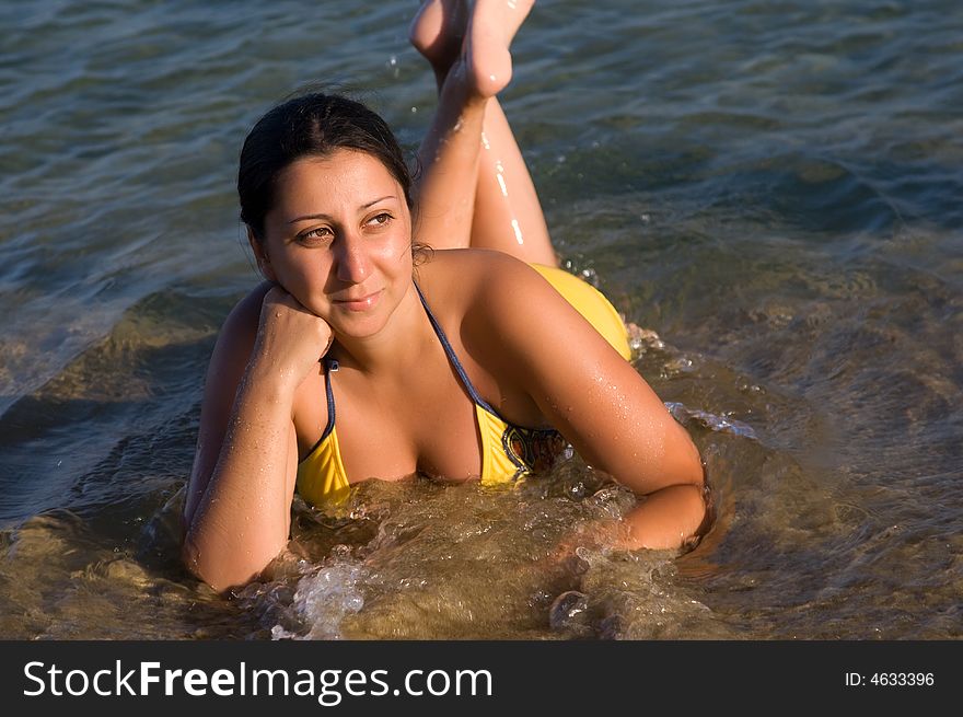 Beautiful Woman laying by the shore of the Aegean Sea with a golden tan