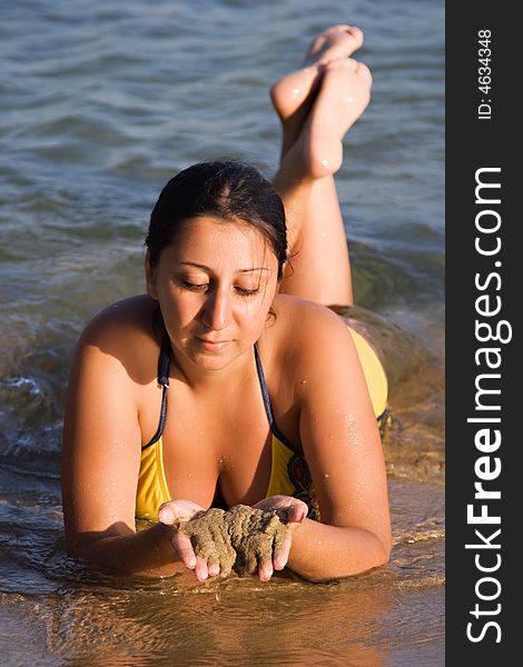 Beautiful Woman laying by the shore of the Aegean Sea with a golden tan