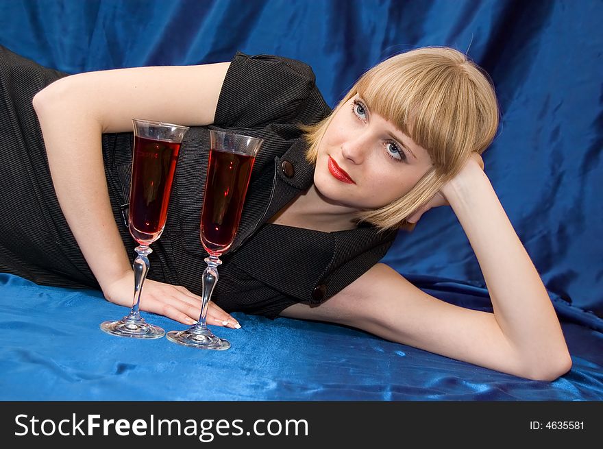 The blonde with a wine glass lays on blue background