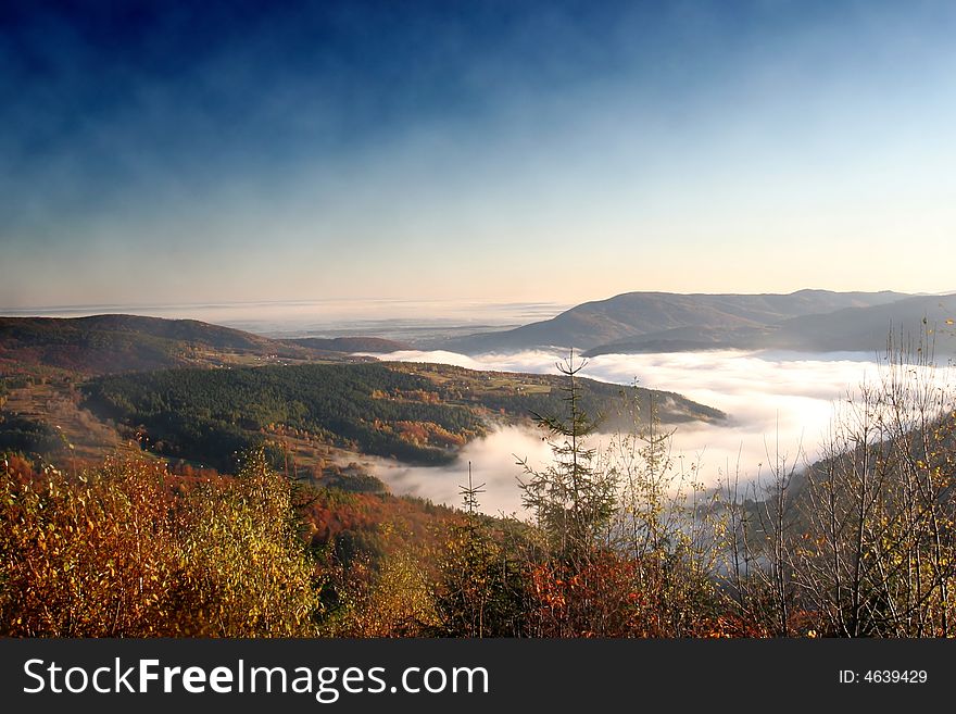 Mist between mountains in sunny autumn day