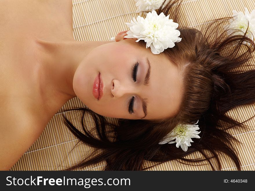 Portrait of Fresh and Beautiful brunette woman laying on bamboo mat