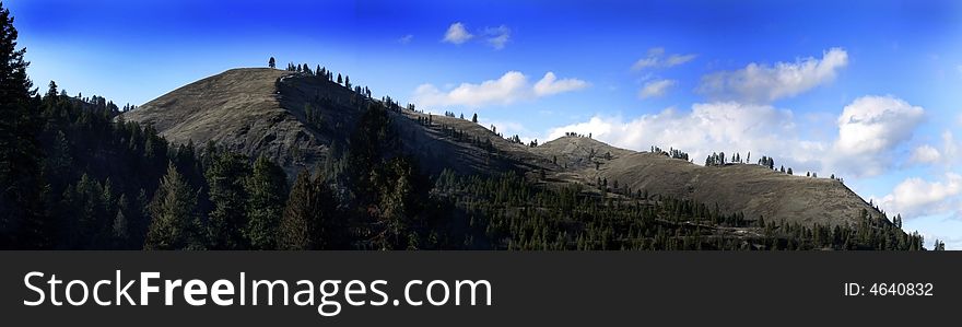 Panoramic of mountains with trees in the foreground and clouds in the background. Panoramic of mountains with trees in the foreground and clouds in the background.