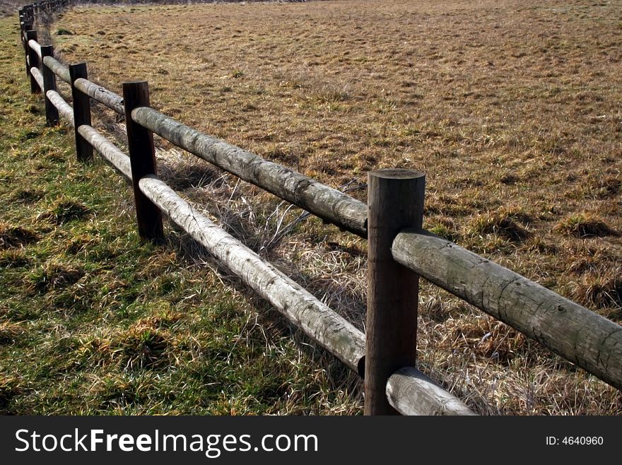 A wooden rail fence bordering a grass field. A wooden rail fence bordering a grass field.