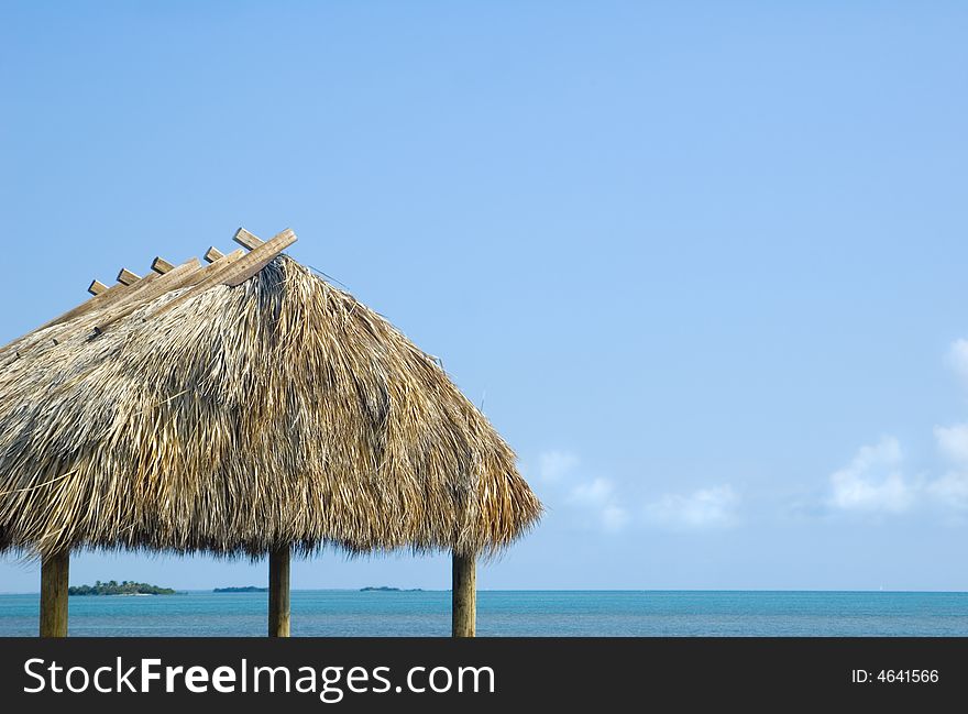 Tropical hut with thatched roof over caribbean blue water