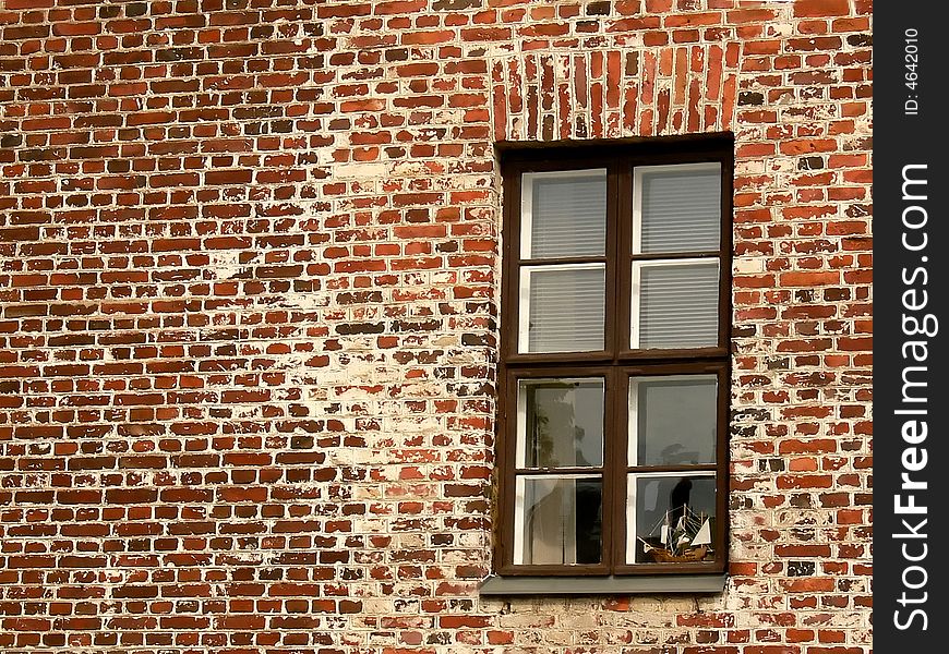 Toy ship in a window on a brick wall