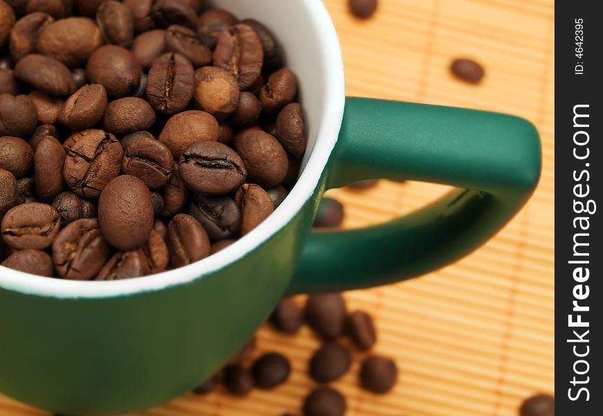 Dark coffee beans in a dark green cup. Dark coffee beans in a dark green cup