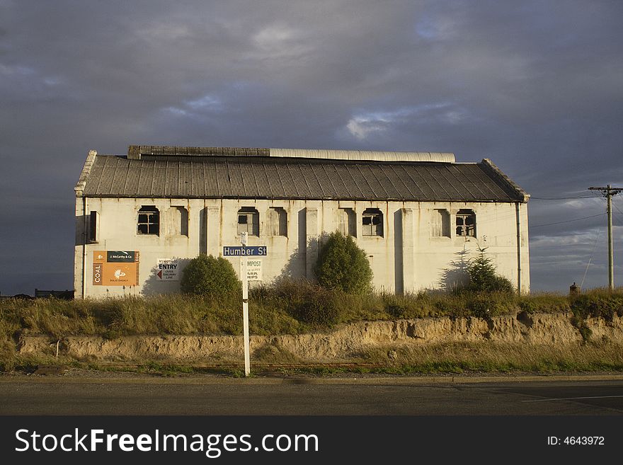 Old building,warehouse in small city New Zealand, bathed in evening sun with dark stormy clouds. Old building,warehouse in small city New Zealand, bathed in evening sun with dark stormy clouds