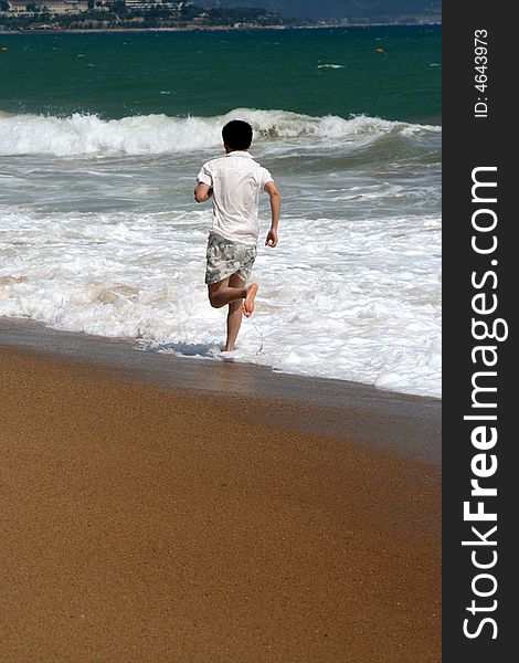 A man running along beach with ocean waves