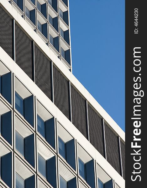 Architectural detail of a modern high-rise building with blue sky serving as the background. Architectural detail of a modern high-rise building with blue sky serving as the background.