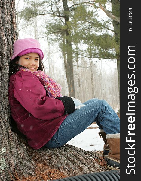 Nine year old girl sitting against tree in winter. Nine year old girl sitting against tree in winter
