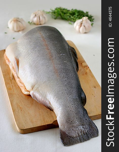 Large slab of tail portion of fresh Atlantic salmon on wooden chopping board
