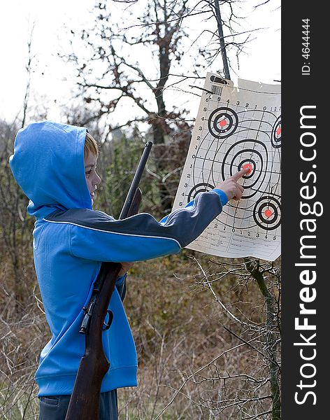 Boy checking his target while holding his rifle. Boy checking his target while holding his rifle